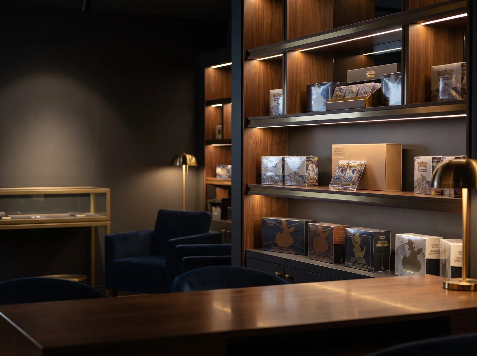 Sealed Pokémon elite trainer boxes and booster boxes displayed on warm-lit walnut shelving.